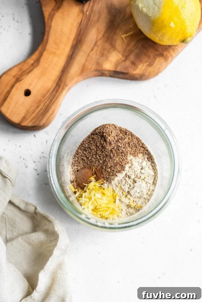Dry ingredients for apple pie overnight oats in a glass jar, including oats, flax, cinnamon, nutmeg, and vanilla protein powder.