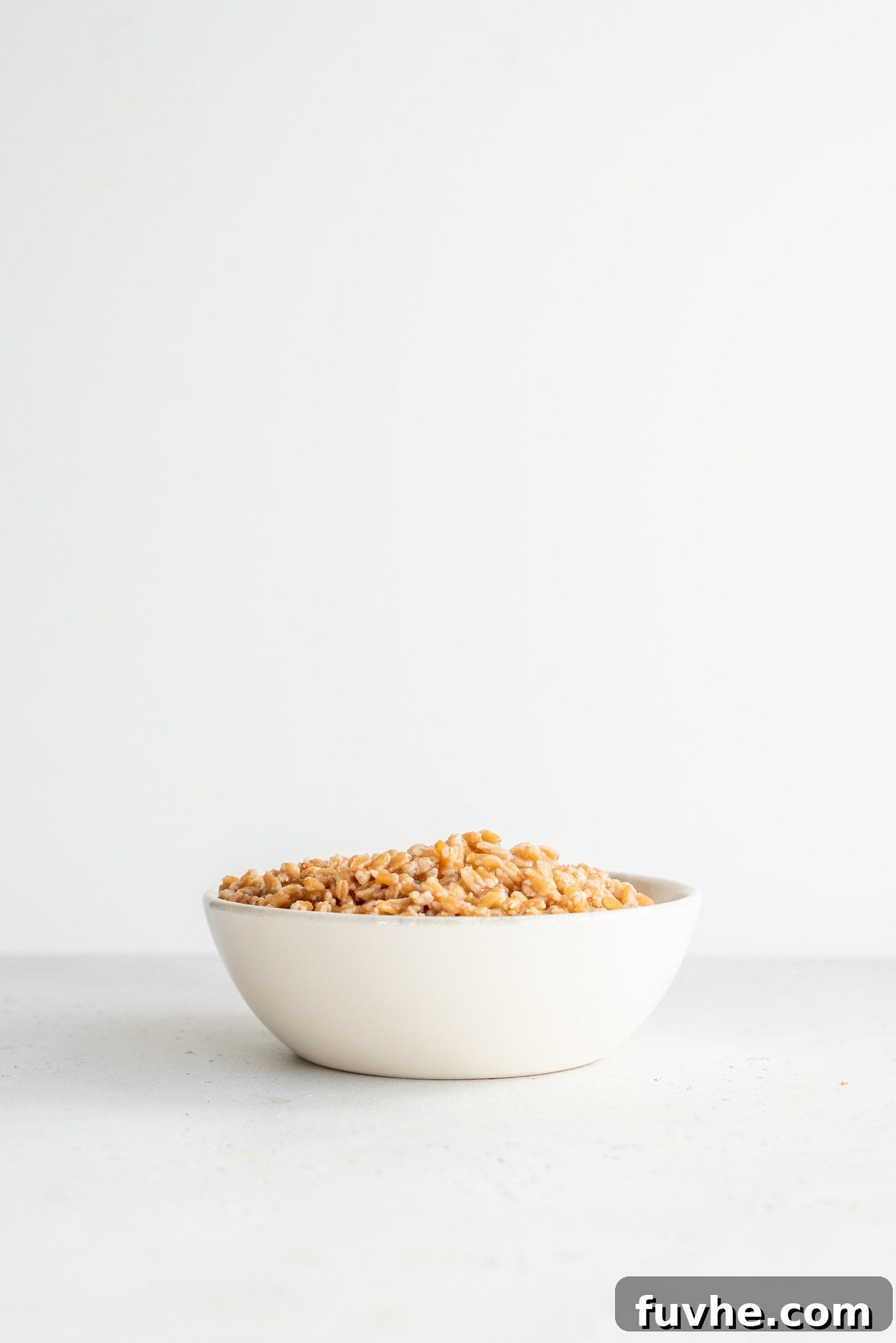 Perfect Instant Pot Farro 2 A beautifully presented bowl of perfectly cooked farro, garnished with fresh herbs, resting on a pristine white surface, highlighting its hearty and inviting texture.
