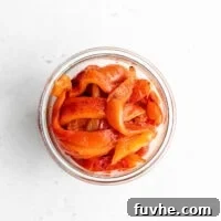 Overhead shot of sliced roasted red peppers in a jar.