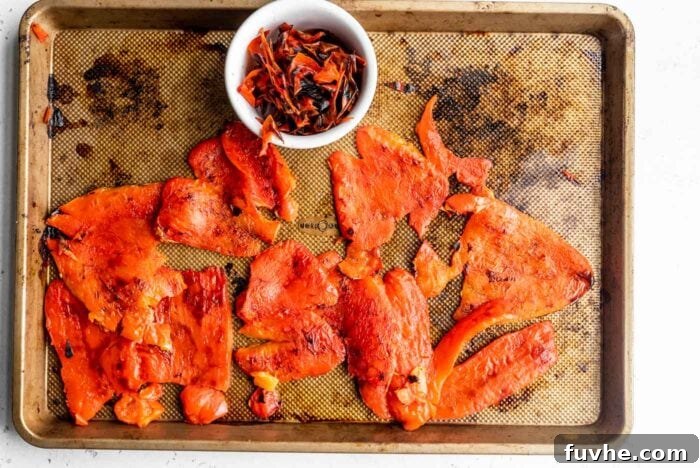 Perfect Roasted Peppers 7 Smooth, peeled roasted red pepper halves rest on a metal pan, showcasing their vibrant color and tender texture.