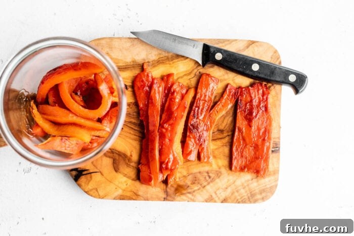 Perfect Roasted Peppers 8 Neatly sliced roasted red peppers arranged on a wooden cutting board, ready for use or storage.