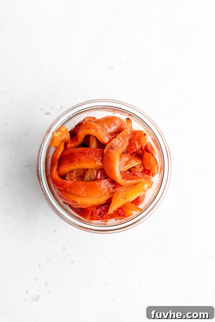 Perfect Roasted Peppers 9 An overhead shot showcasing beautifully sliced roasted red peppers neatly packed into a glass jar.
