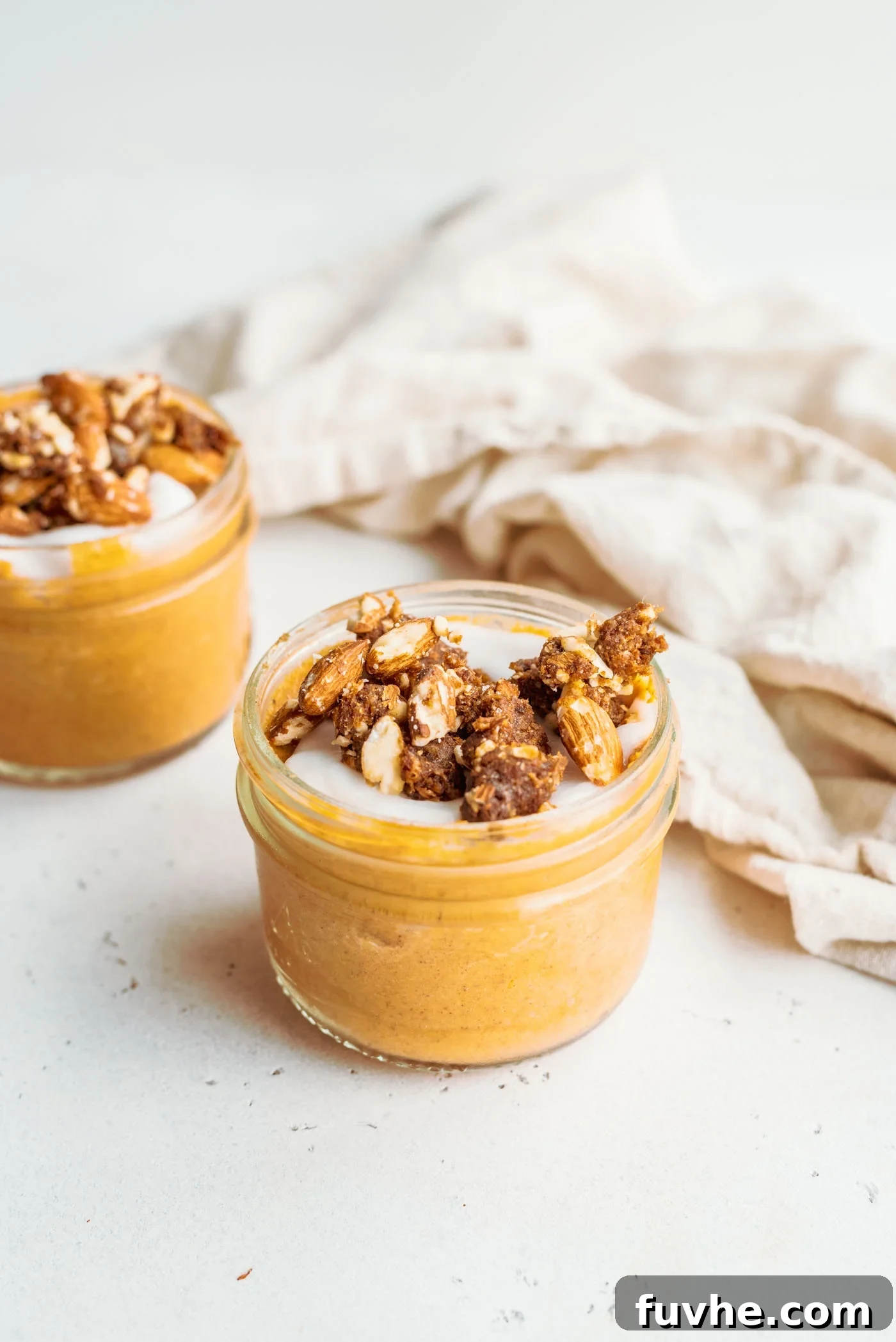 Small jar of healthy vegan pumpkin mousse topped with crumbled pecans, ready to be enjoyed.