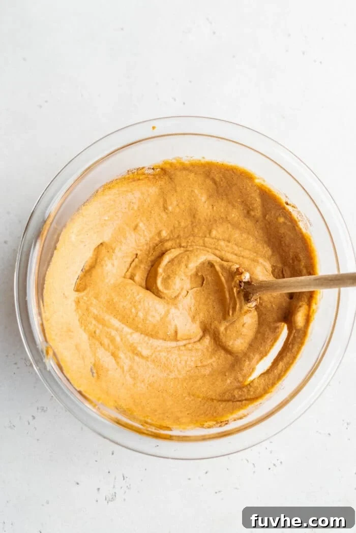 The pumpkin mousse mixture in a mixing bowl with a wooden spoon, showcasing its smooth texture.