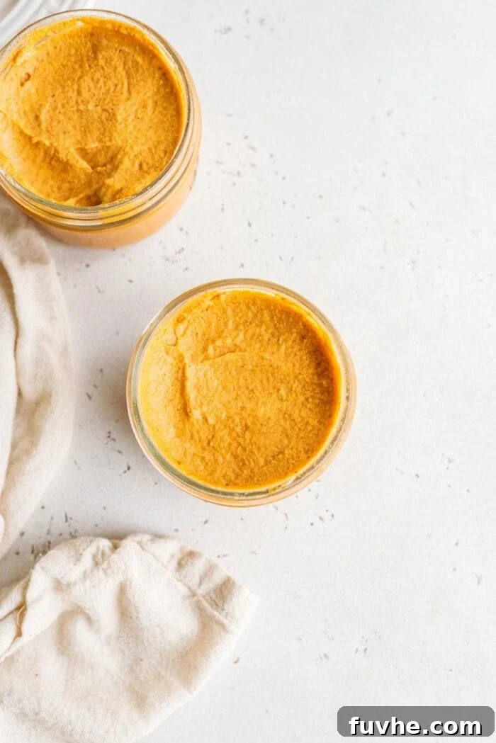 Two small glass jars filled with prepared pumpkin mousse, chilling in the refrigerator.