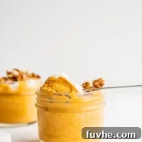 A spoon scooping creamy vegan pumpkin mousse from a small jar.