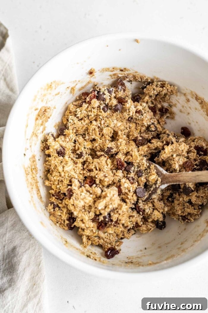 A white mixing bowl full of raw, perfectly mixed cookie dough, illustrating its smooth consistency.