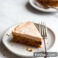 A large slice of raw carrot cake on a white plate with a fork.