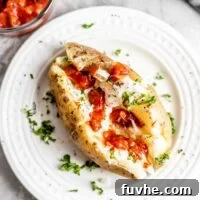Perfect Instant Pot Baked Potatoes 11 Overhead shot of a baked potato with sour cream, parsley and salsa on a small white plate.