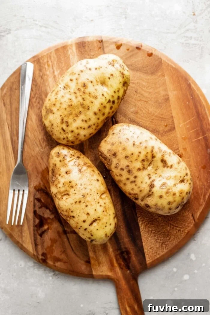Perfect Instant Pot Baked Potatoes 4 3 Russet potatoes on a cutting board with a fork.