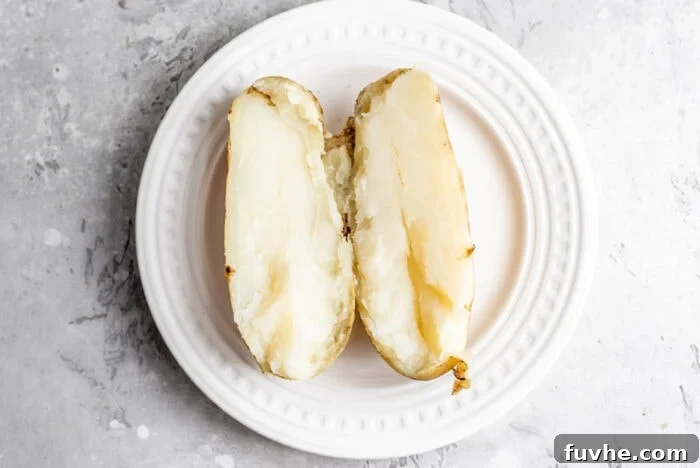 Perfect Instant Pot Baked Potatoes 6 A sliced open baked Russet potato on a small white plate,
