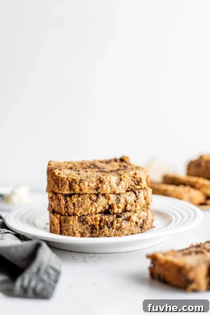 Decadent Vegan Chocolate Chip Banana Loaf 2 A stack of three irresistibly moist and easy vegan banana bread slices on a clean white plate, speckled with chocolate chips.