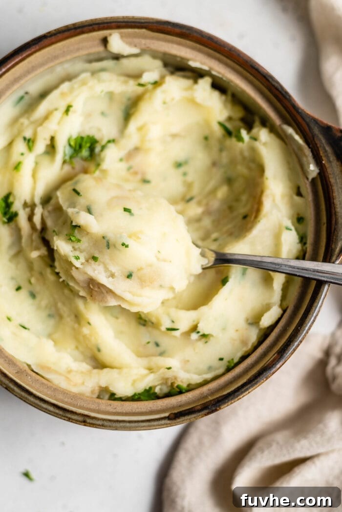 A spoon scooping a large spoonful of mashed potatoes out of a serving dish.