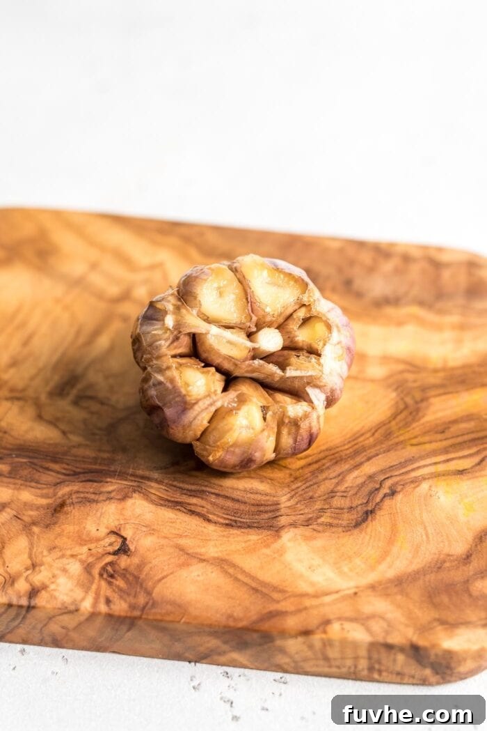 A whole bulb of roasted garlic on a cutting board.