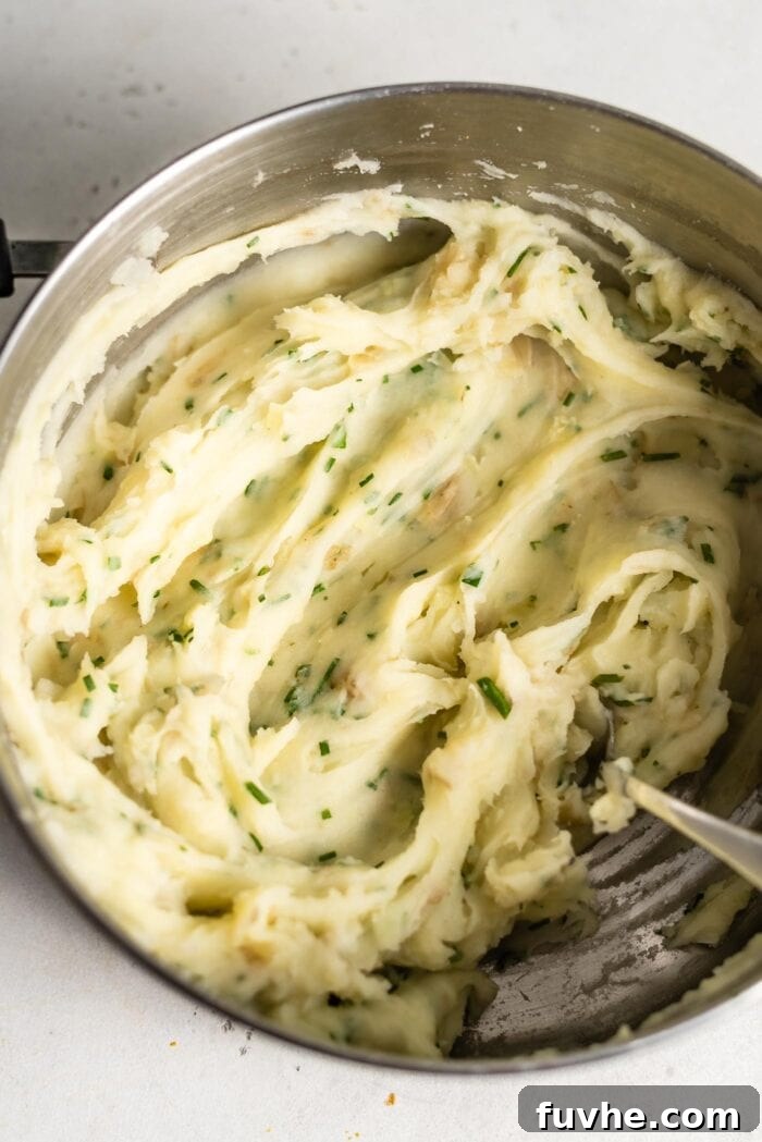Mashed potatoes with fresh chives in a large pot.