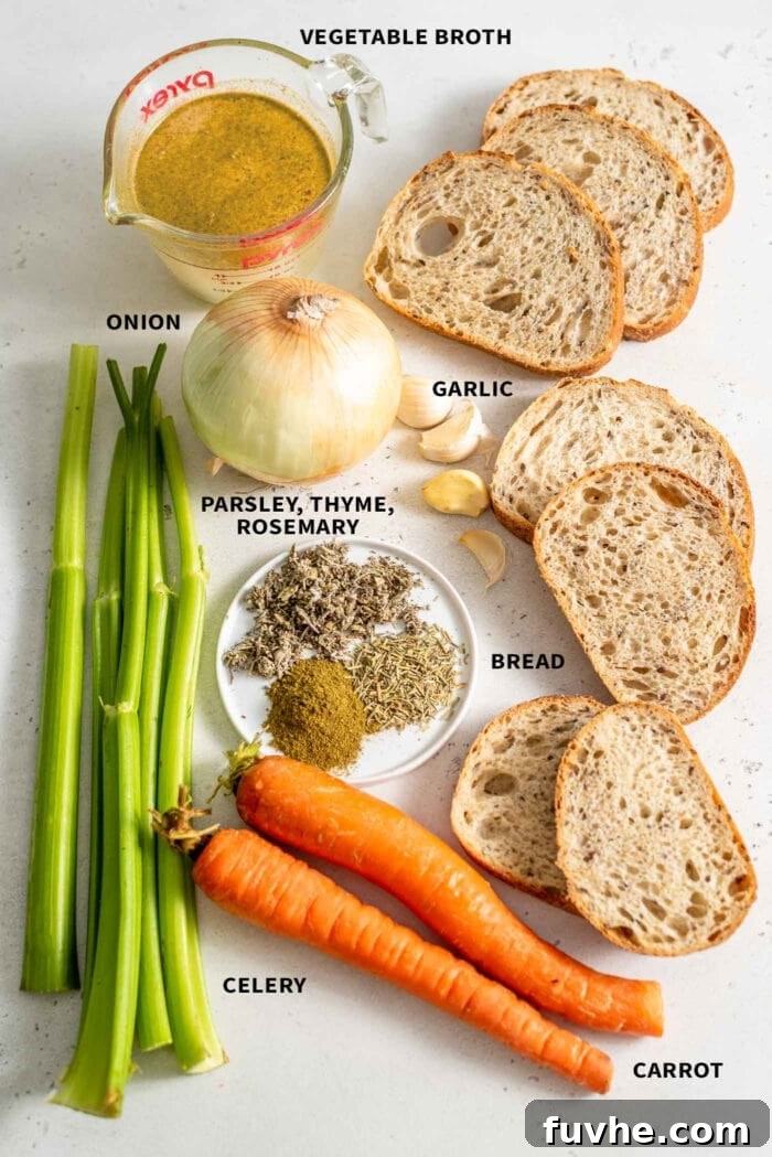A collection of fresh, vibrant ingredients for vegan stuffing, including diced celery, carrots, a loaf of bread, fresh herbs, vegetable broth, garlic cloves, and a yellow onion, neatly arranged on a pristine white surface.