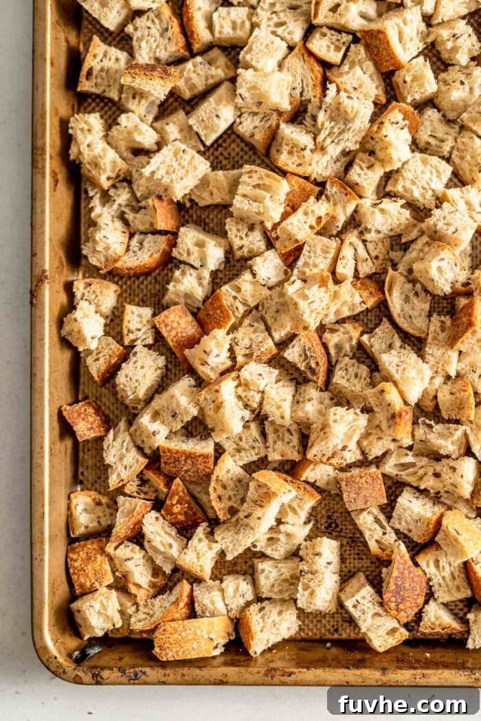 Uniformly cubed bread pieces spread evenly on a baking tray, ready for drying or toasting to achieve the ideal texture for stuffing.