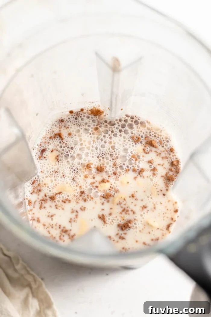 Festive Vegan Nog 5 Almond milk poured into a blender with cashews, dates, nutmeg, and cinnamon.
