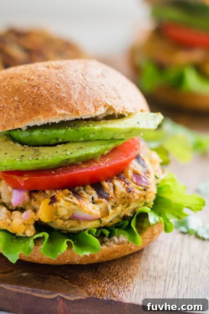 Close up of a veggie burger on a toasted bun topped with lettuce, tomato and avocado.