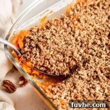 Scooping out a serving of sweet potato casserole out of a baking dish.