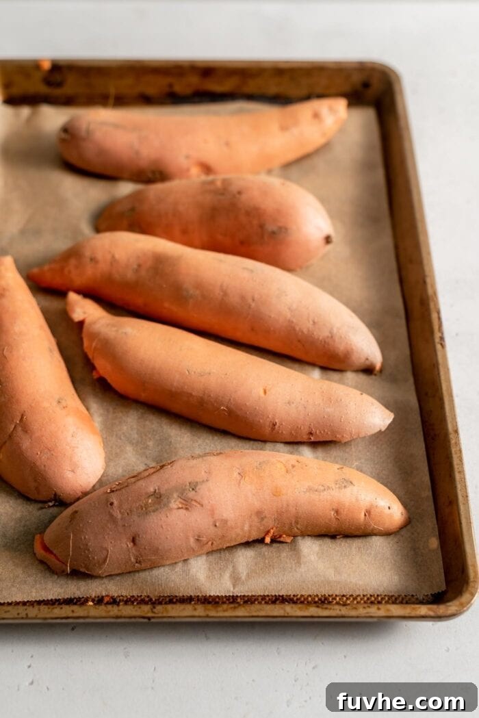 Golden Vegan Sweet Potato Comfort 4 Sweet potatoes cut in half and placed face down on a baking tray lined with parchment paper.