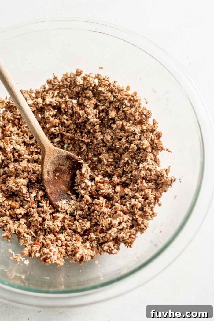 Golden Vegan Sweet Potato Comfort 9 Pecan and oat crumble topping in a mixing bowl with a wooden spoon.