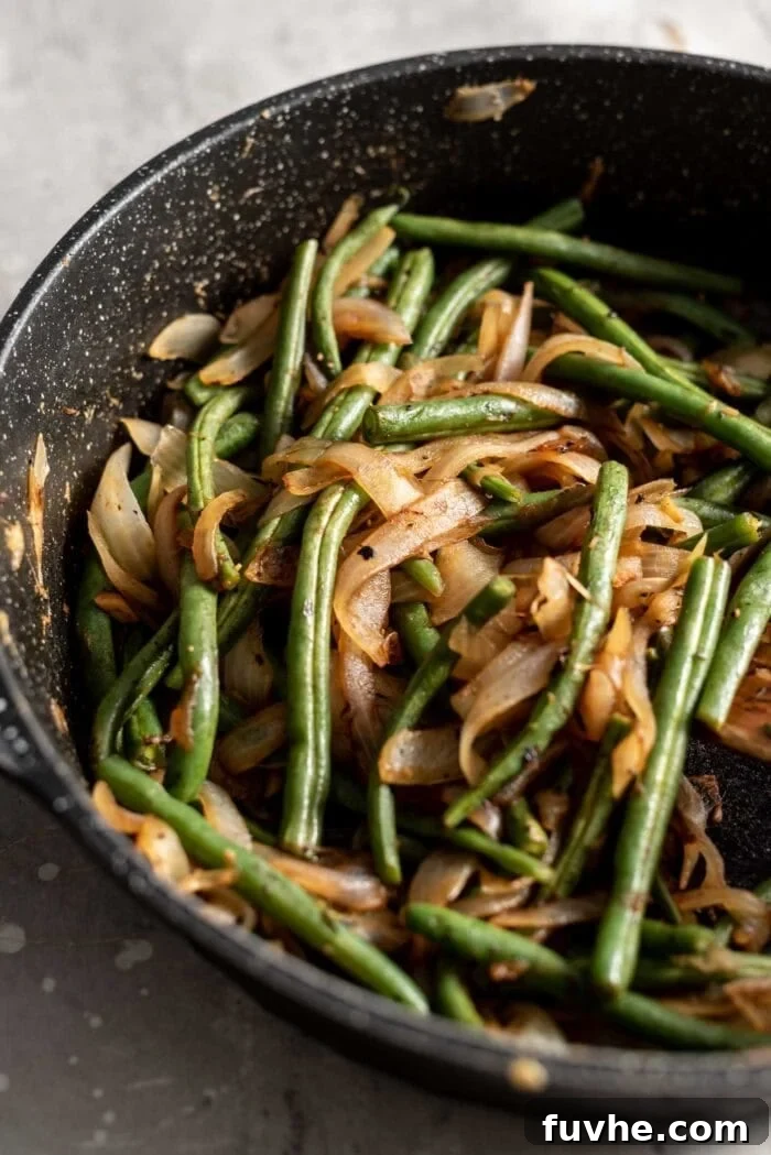 Garlicky Onion Green Bean Sauté 6 Sautéed green beans and onions in a black skillet.