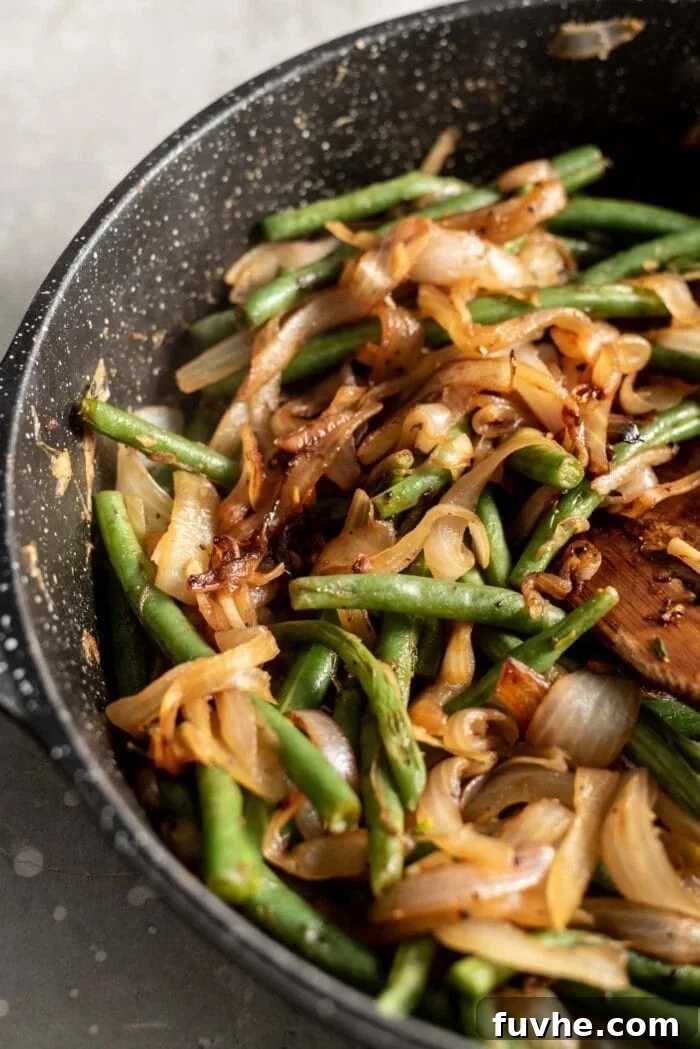 Garlicky Onion Green Bean Sauté 7 Sautéed green beans and onions in a black skillet.