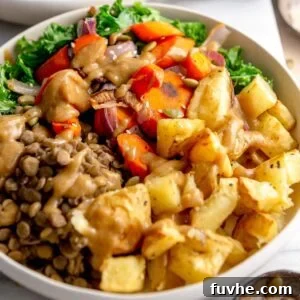Healthy vegan bowl with roasted potatoes, roasted onion and carrot, lentils, kale and gravy.