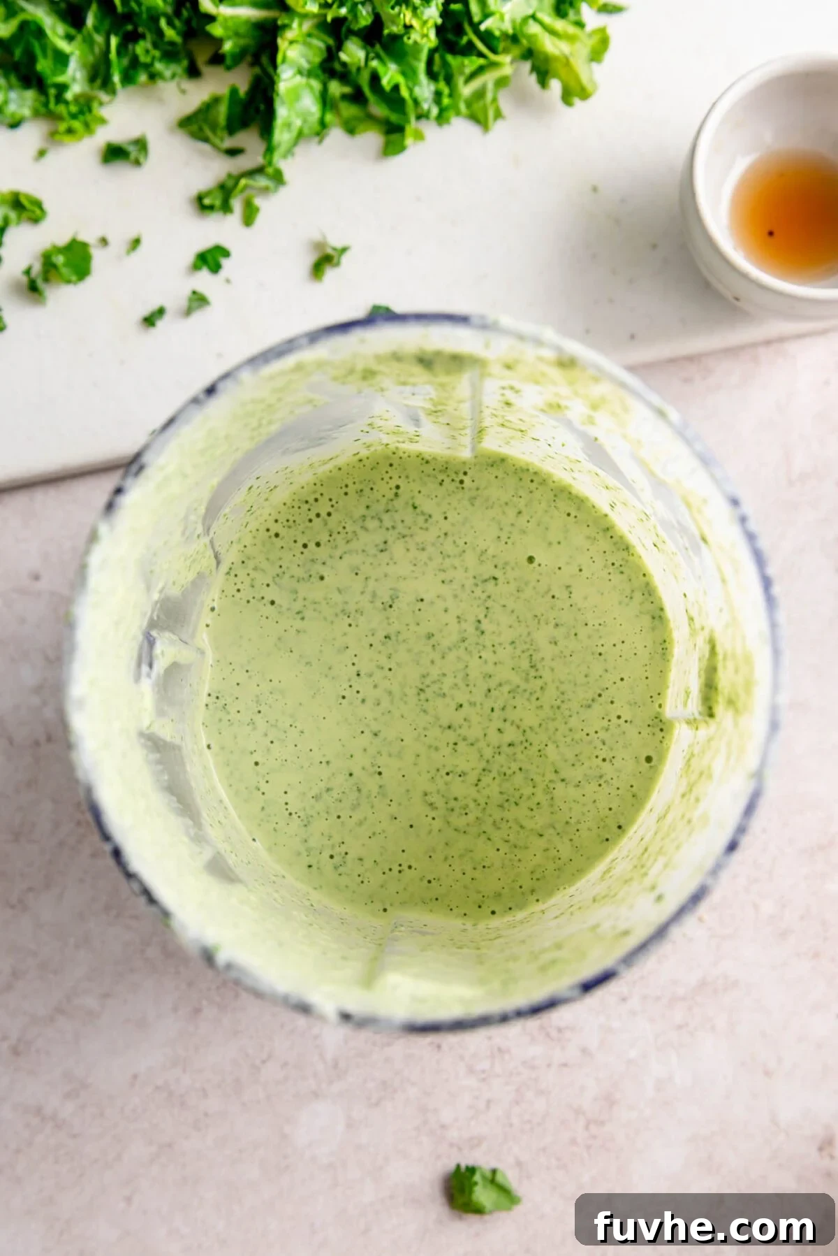 A vibrant green creamy tahini dressing blending in a small food processor.