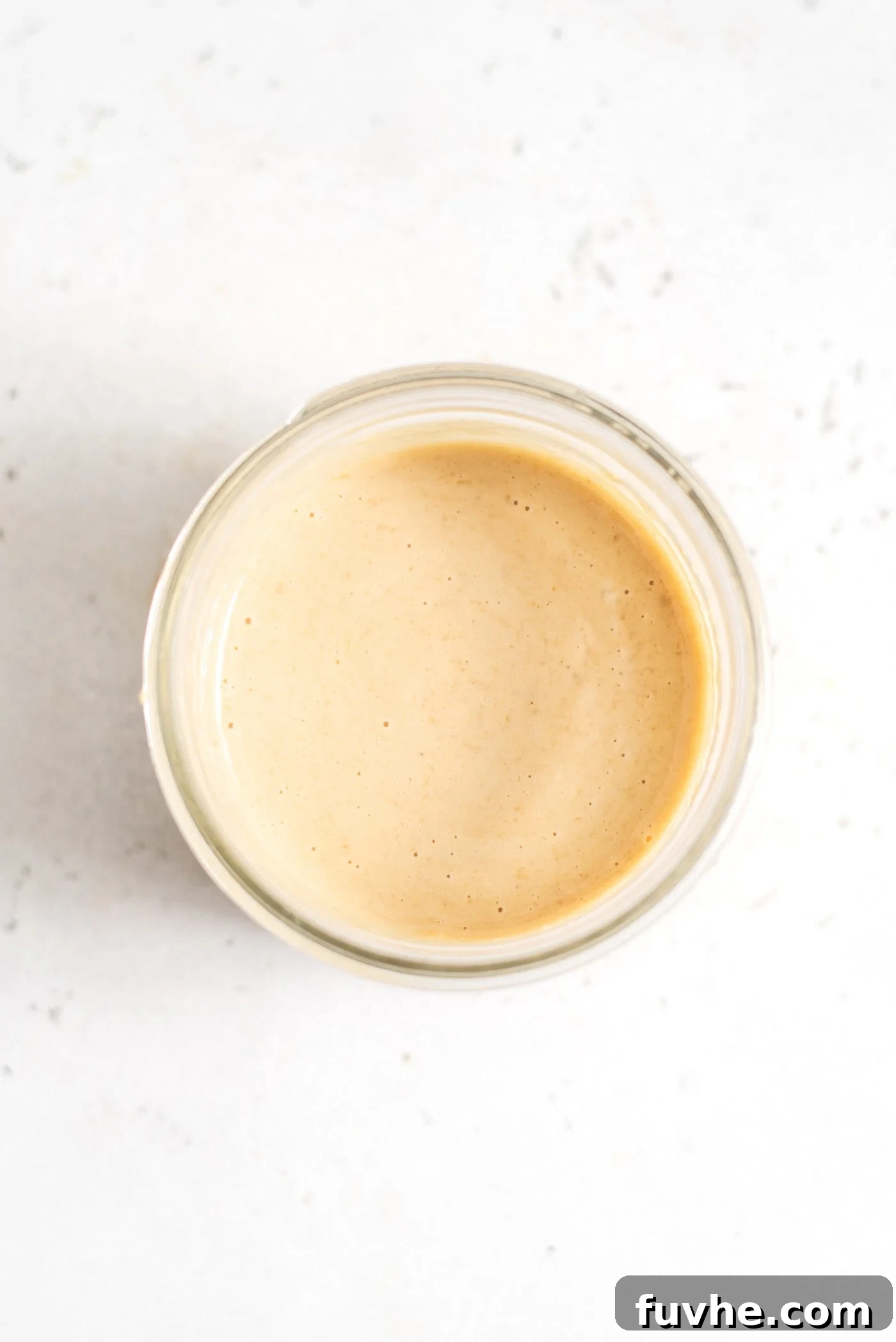 Creamy miso tahini dressing in a small glass jar, elegantly presented and ready to be drizzled over your favorite dishes.