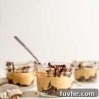 Three decadent vegan peanut butter mousse parfaits in small glass jars.
