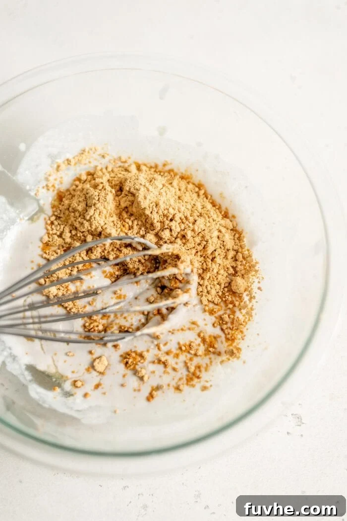 Coconut cream and powdered peanut butter in a mixing bowl with a whisk, showing the initial stages of mousse preparation.