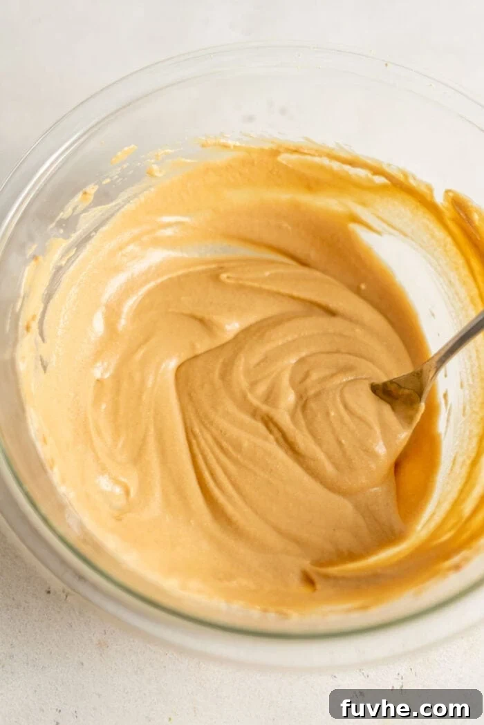 Smooth, mixed peanut butter mousse in a mixing bowl with a spoon, demonstrating its creamy texture.