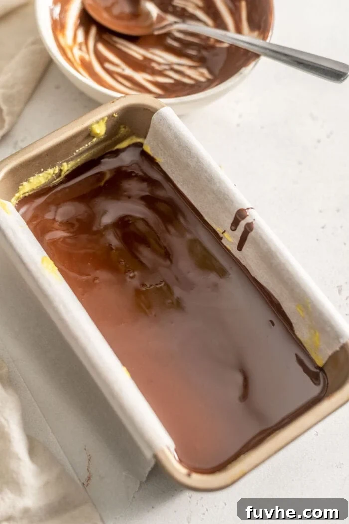 Vegan Nanaimo Bar Delight 10 Melted chocolate in a loaf pan lined with parchment paper.