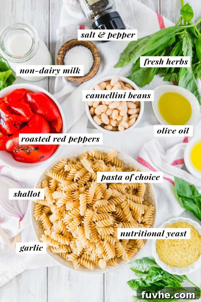 A visual lineup of fresh and pantry ingredients needed to make creamy vegan roasted red pepper pasta, including cannellini beans, nutritional yeast, and shallots.