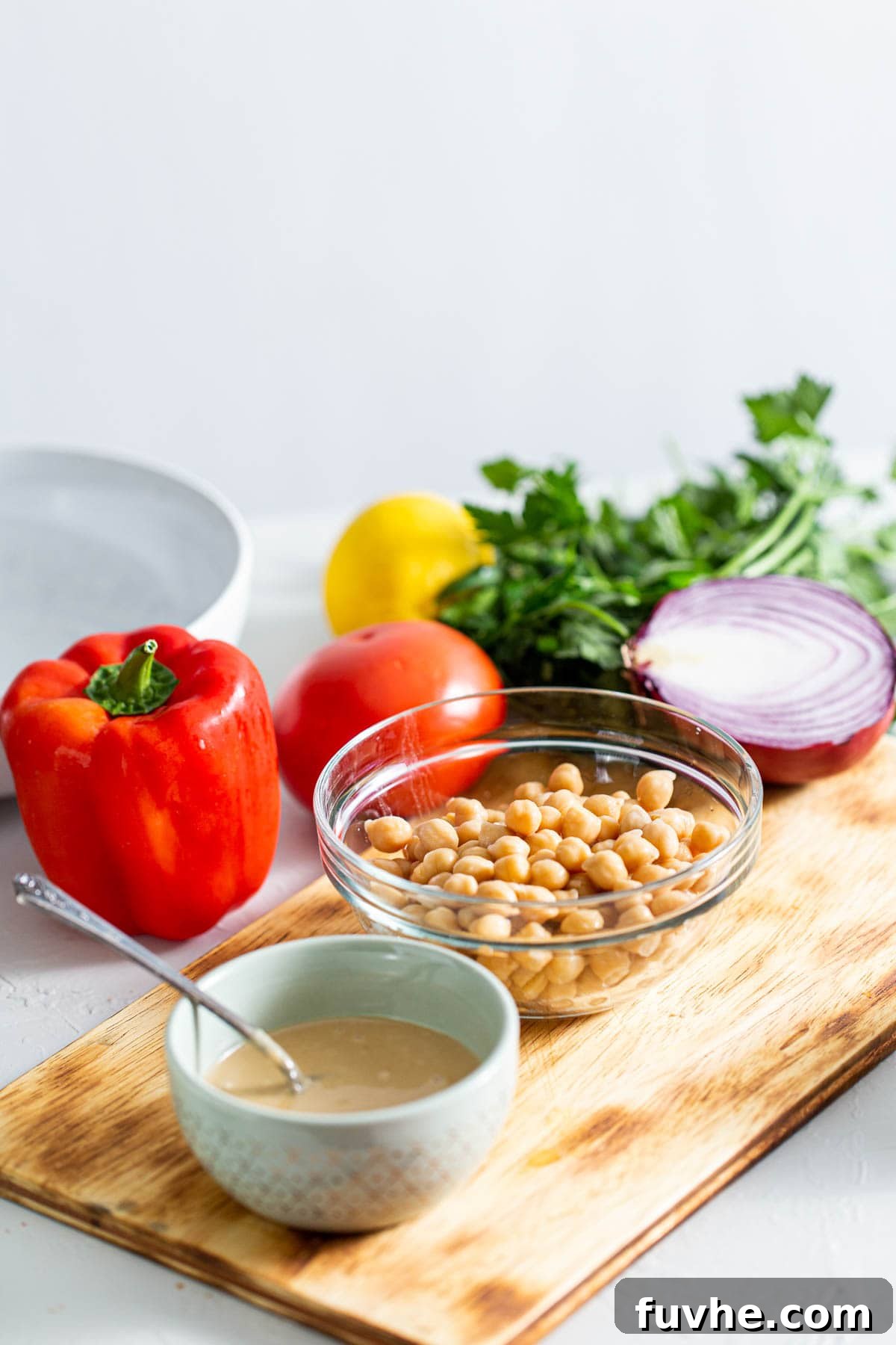 High-Fiber Powerhouses 2 Chickpeas, tahini, bell pepper, onion, parsley and red onion on a cutting board.