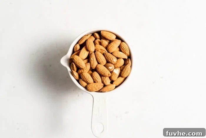 Plant-Based Parm Perfection 3 Raw almonds in a measuring cup, showcasing the primary ingredient for homemade vegan parmesan.