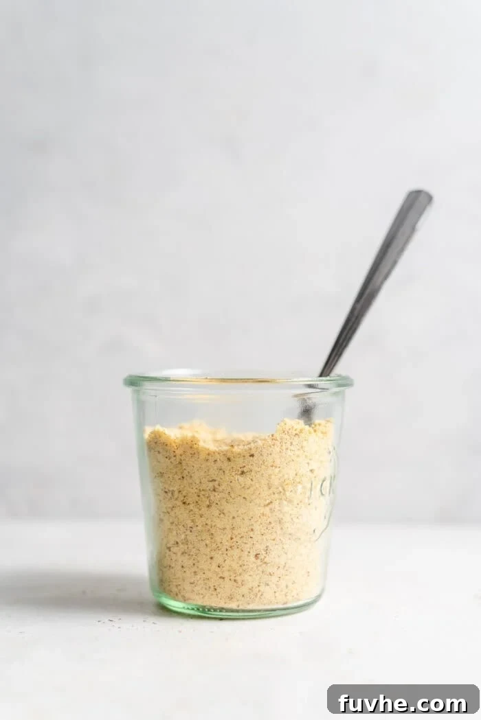 Plant-Based Parm Perfection 6 Vegan parmesan cheese in a jar with a small serving spoon, ready to be used.