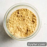 Vegan almond parmesan in a glass jar, displaying its fine texture and readiness for use.
