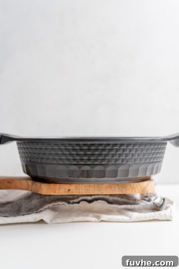 A heavy black frying pan serving as a weight on a wrapped block of tofu.