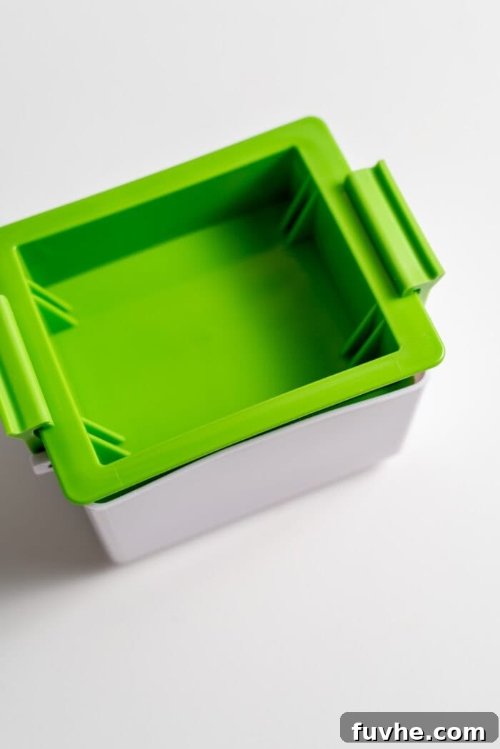 A sleek, sealed green tofu press, demonstrating its compact and mess-free design.