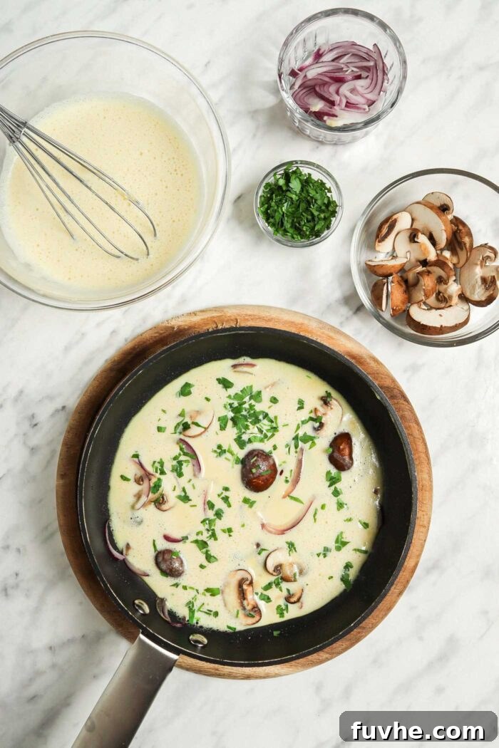 Fluffy Plant-Based Chickpea Omelette 6 Chickpea flour omelette cooking in a pan with mushroom, parsley and red onion.