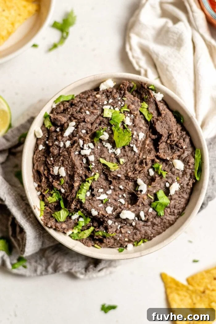 Quick and Creamy Instant Pot Black Beans 5 A vibrant bowl of vegan refried black beans topped with fresh cilantro, ready to be enjoyed.