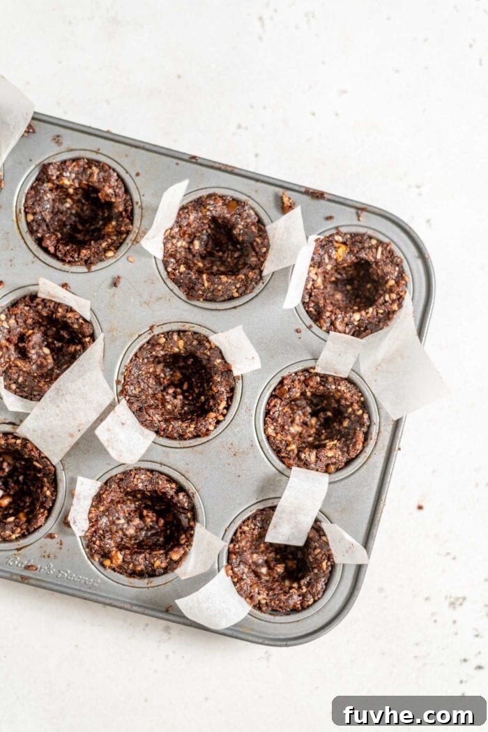 Effortless Chocolate Caramel Temptations 7 Unfilled chocolate tarts in a mini muffin tin.