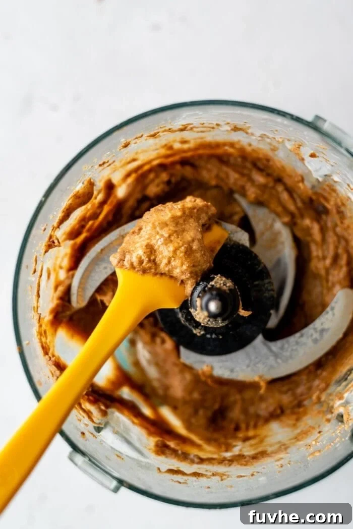 Effortless Chocolate Caramel Temptations 8 Blended, creamy caramel in a food processor with a spatula.