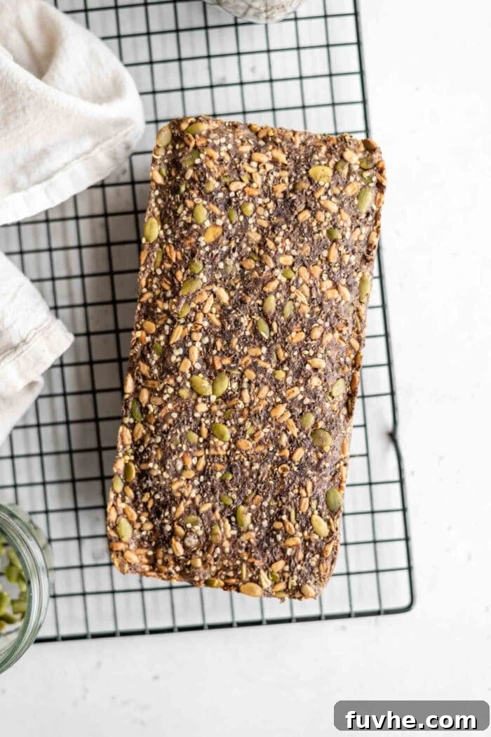 A freshly baked, rustic loaf of seed bread, showcasing a rich array of visible seeds, gently resting on a wire cooling rack to achieve its perfect texture before slicing.
