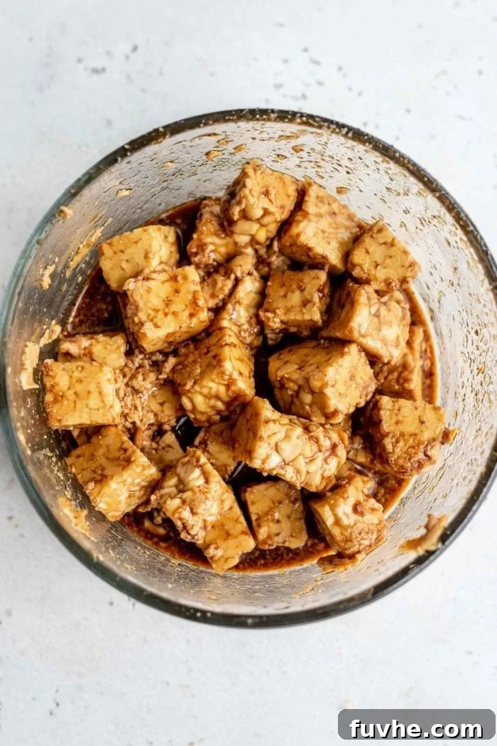 Wholesome Vegan Tempeh Buddha Bowl 3 Cubed tempeh in a glass bowl with a rich, savory marinade, ready to absorb flavor.