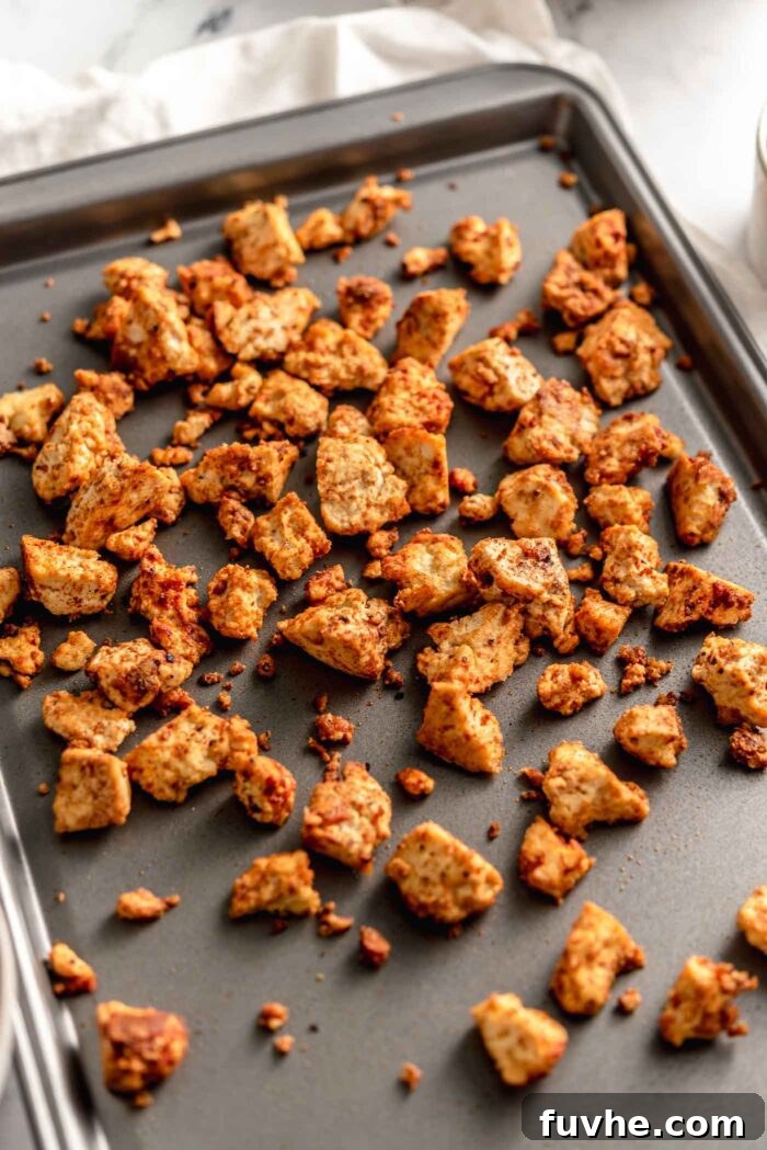 Crispy and golden-brown shawarma-spiced tofu pieces spread evenly on a baking tray, having just come out of the oven.