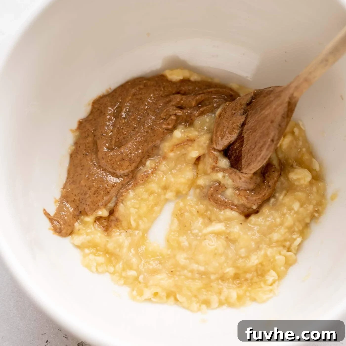 Mashed banana with almond butter in a mixing bowl, showing a smooth, creamy consistency.